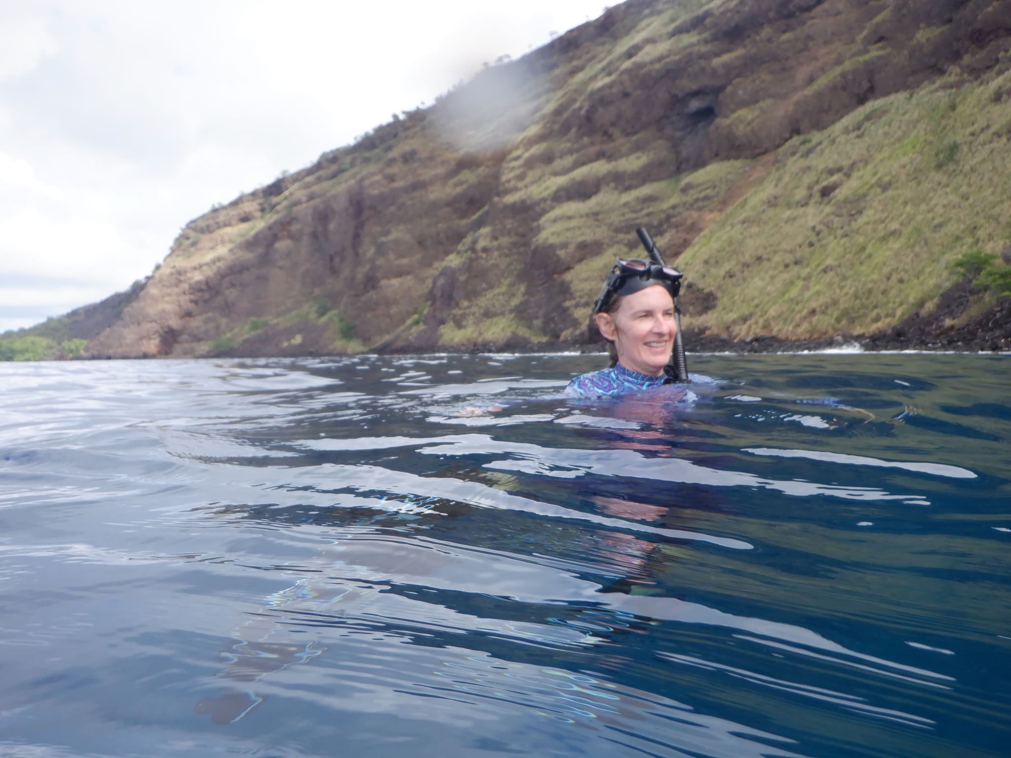 Deona snorkeling in the ocean with coastal cliffs